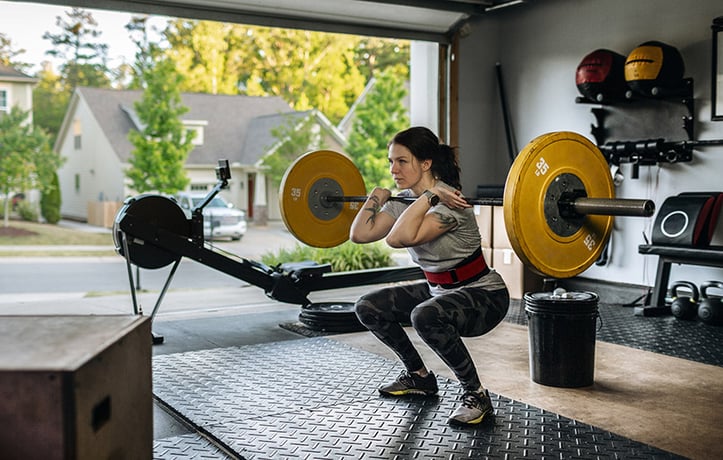 a woman doing a front squat in her garage gym