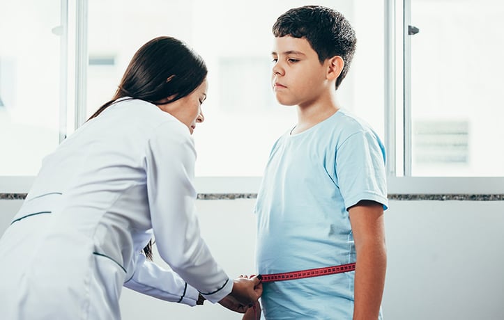 a medical professional measuring the waist of a youth