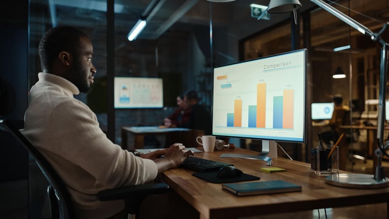 Homem sentado, utilizando seu computador para ver os dados de sua empresa.
