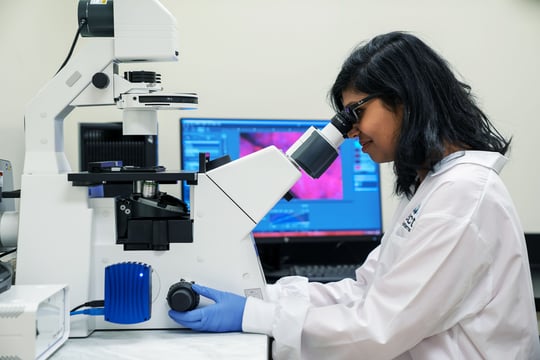 Aspect scientist looking through microscope