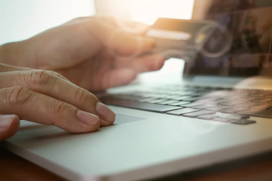 close up of hands using laptop and holding credit card as Online shopping concept