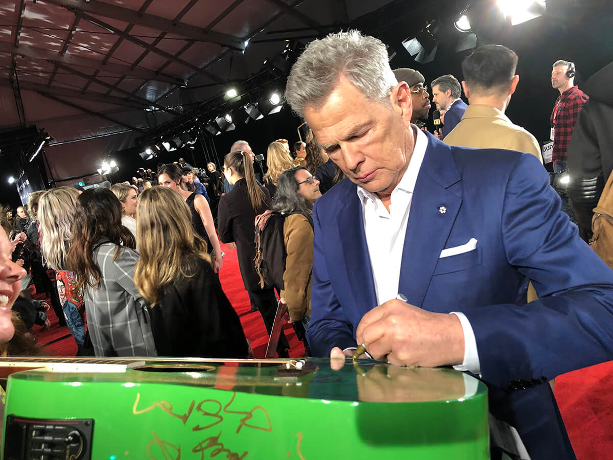 David Foster at 2019 Junos red carpet signing Start.ca green guitar