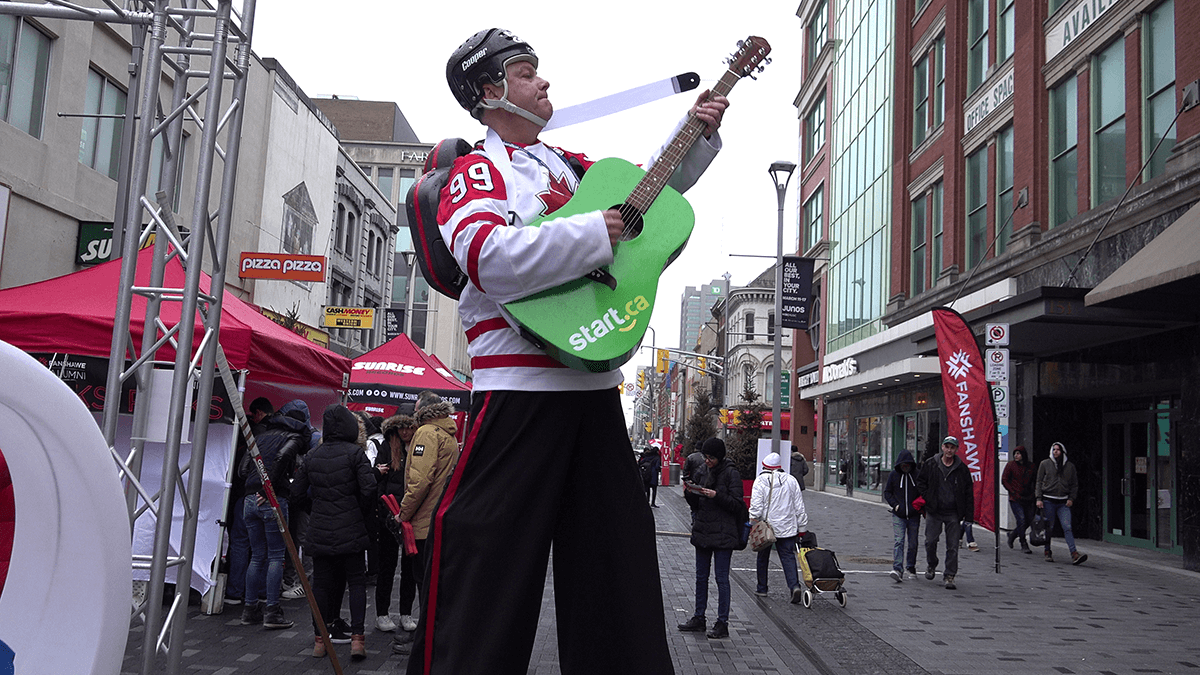 guy on stilts playing green Start.ca guitar during 2019 JUNOS festival