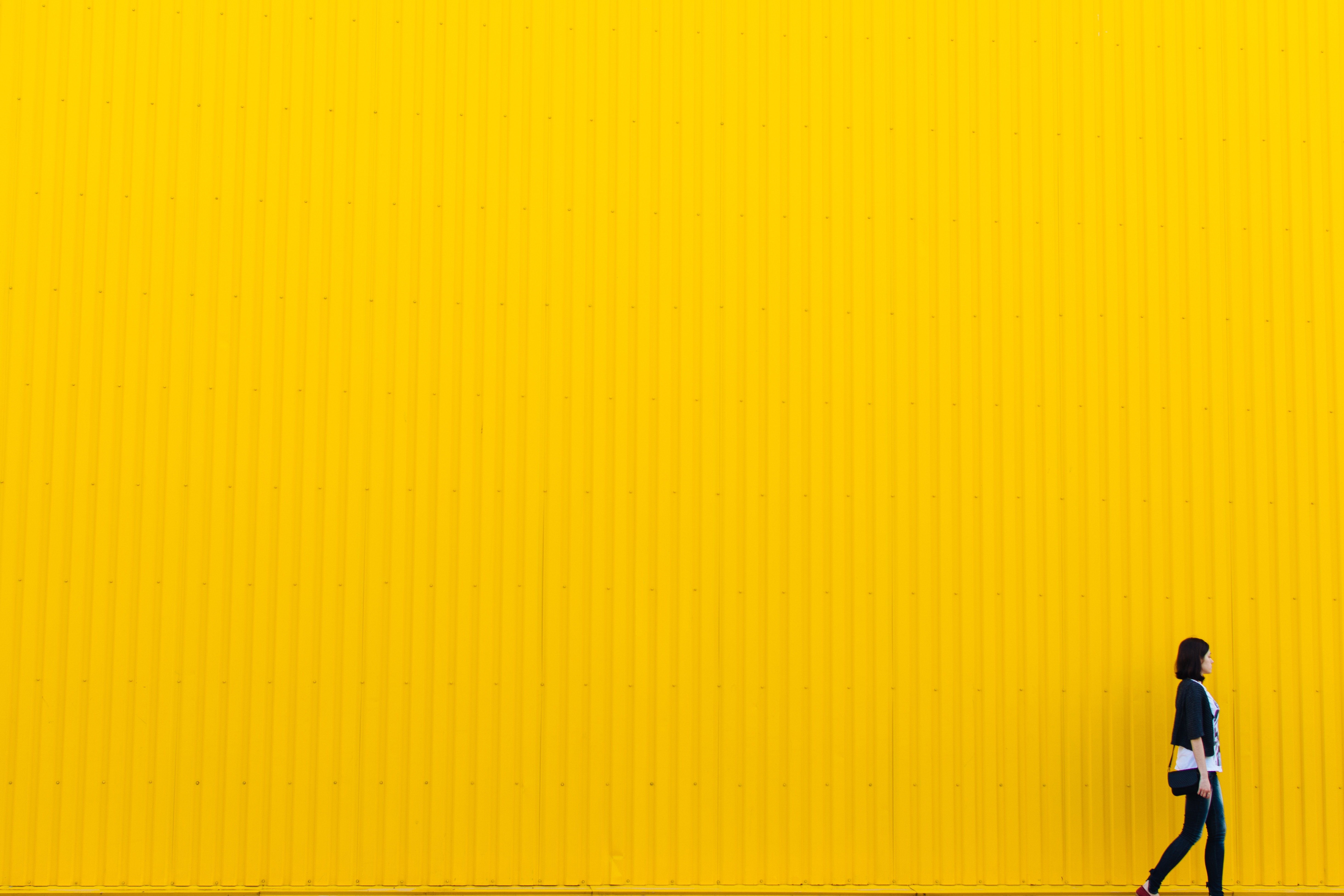 Woman standing next to yellow wall