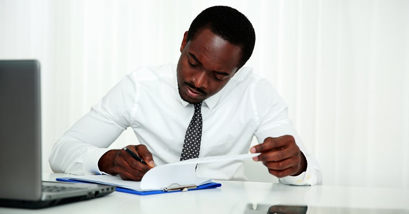 African man signing document in office