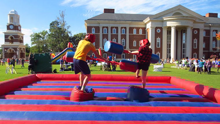 Two pre-teens playing inflatable joust at party