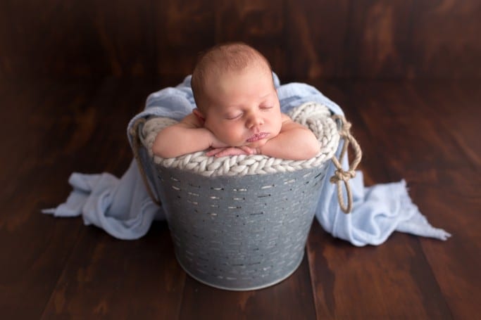 newborn baby photo posed forward facing in a prop bucket