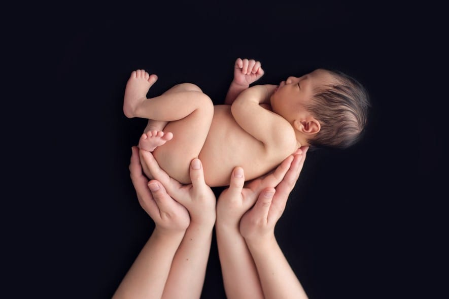 newborn baby photo lying in parents' hands