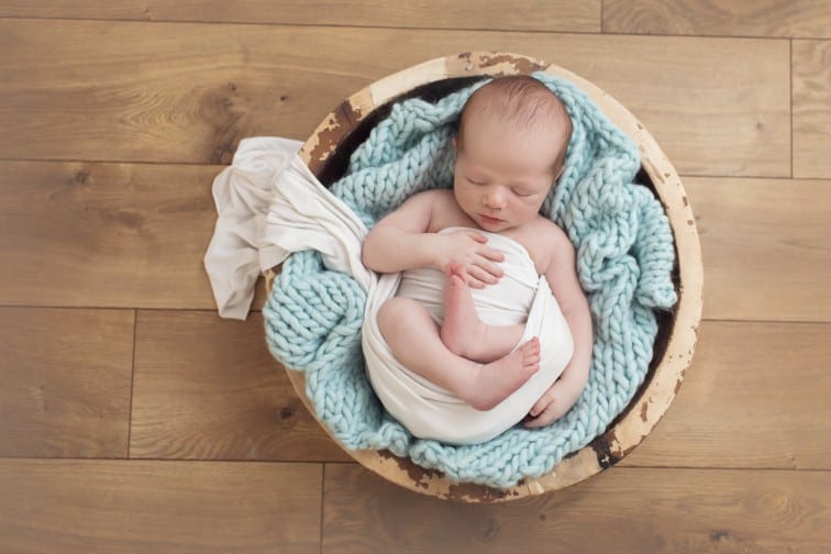 newborn baby photo partially swaddled in a prop basket