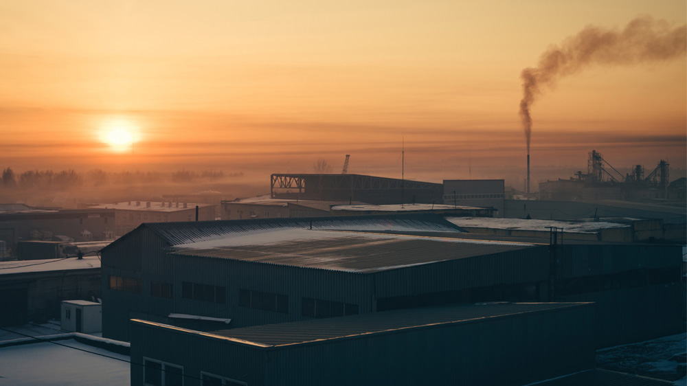 Birds-eye view during sunset of factory with smoke coming out during their winter. 