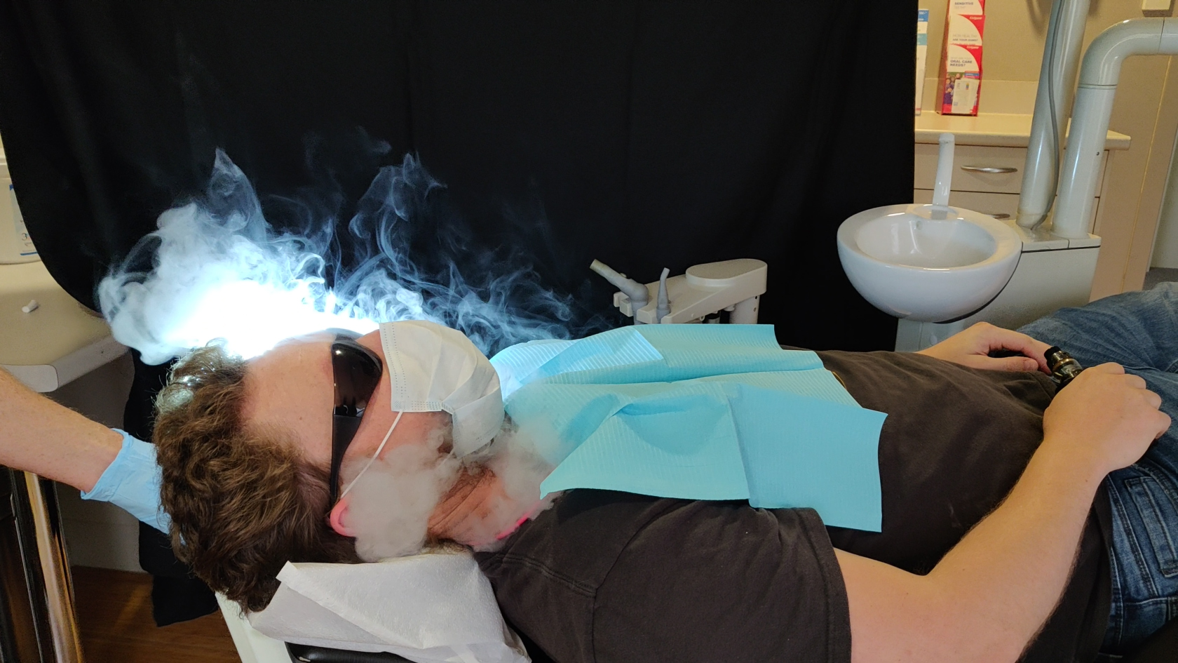 A patient breathes out vape in a mask to show aerosol escape