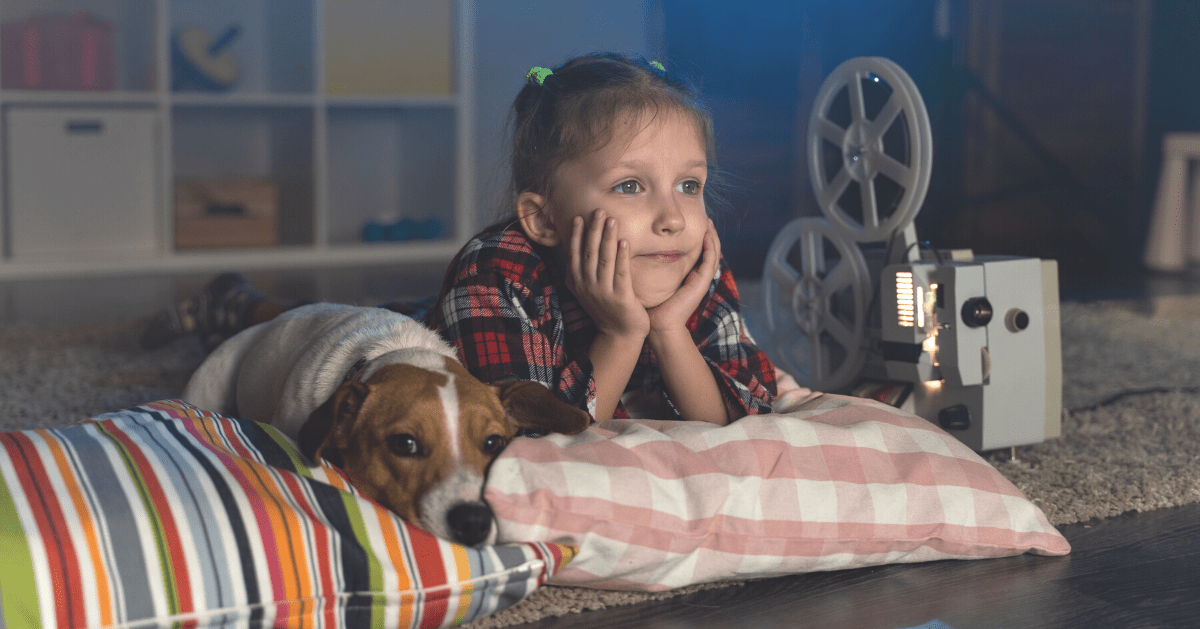 young girl watching old films with pet dog