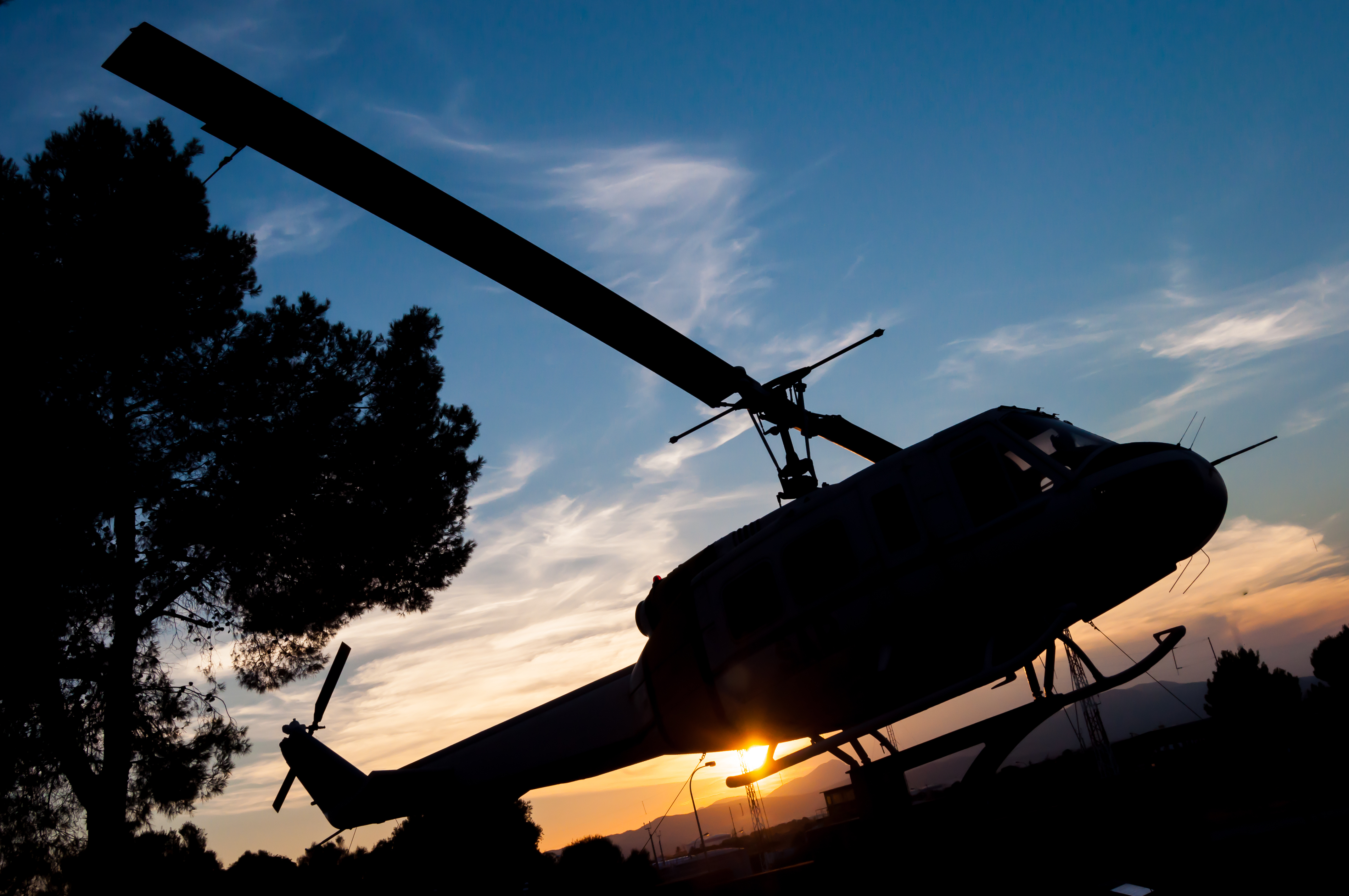 Silhouette of a helicopter on the backdrop of a sunset blue sky, representing aviation career opportunities with M&E