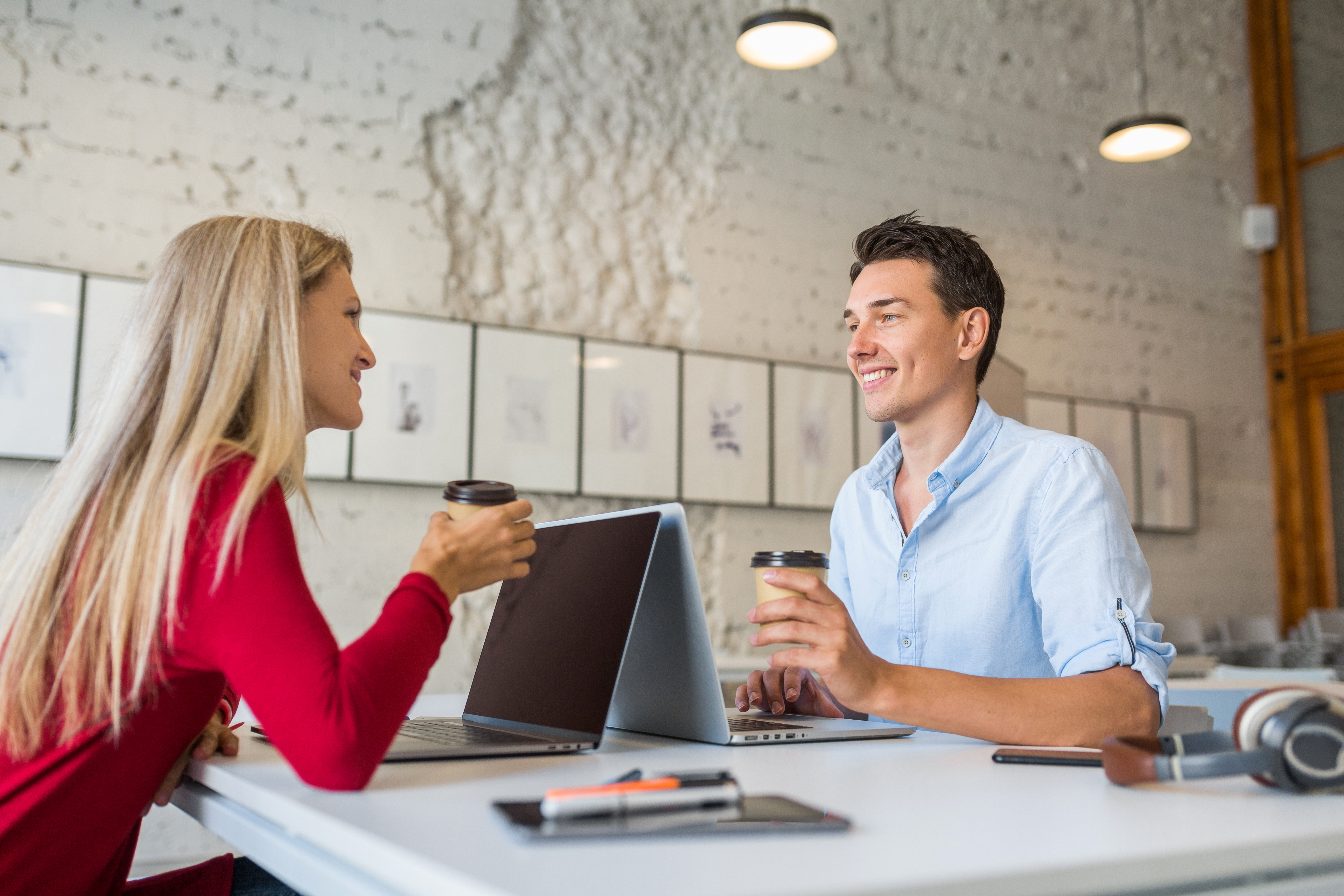 cool-young-man-woman-sitting-table-face-face-working-laptop-co-working-office