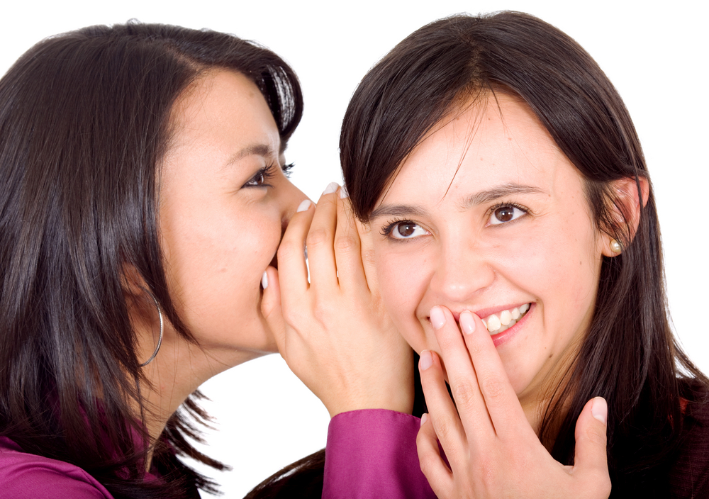 girl telling a secret to another - gossip isolated over a white background