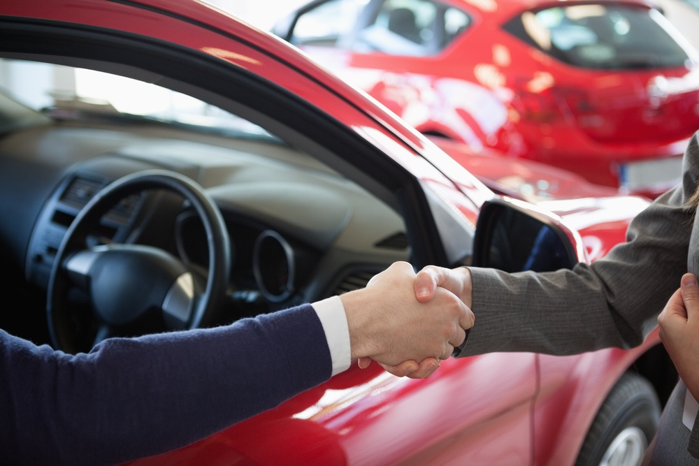 Close up of a man shaking hand to a woman in a dealership