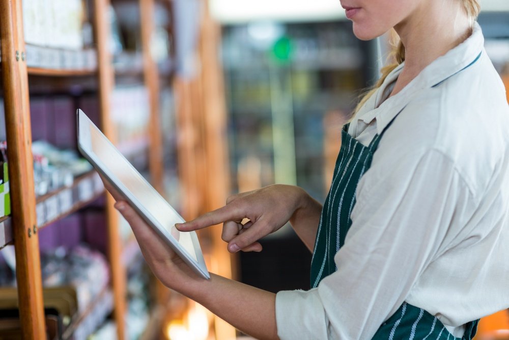 Mid-section of female staff using digital tablet in super market.jpeg