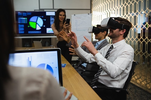 29680940_businessmen-using-virtual-reality-headset-in-conference-room-min